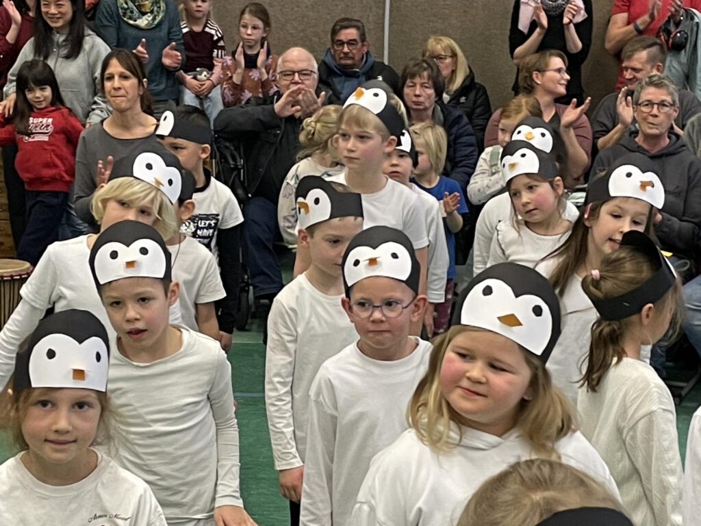 Trommelprojekt an der Marienschule
414 trommelnde Hände - da bebt schon mal der Hallenboden, da klingen tolle Rhythmen durch die Luft und da strahlen vor allem auch 414 leuchtende Augen bei Groß und Klein. Es war mal wieder Trommelzeit in Hauenhorst. Famous Doe vom Trommelzauberteam gastierte für fünf Tage mit dem Stück Bantamba in der Mariengrundschule. Jeden Morgen starteten die 192 Kinder und 15 Erwachsenen gemeinsam mit ihrem sympathischen Trommelchef trommelnd in den Tag. Anschließend wurden in den Gruppen die Rhythmen, Tänze, Lieder und Texte geübt, bis es dann am Donnerstag und Freitag zu vier Aufführungen kam. Eine Generalprobe, eine Aufführung für die Kindergärten aus Hauenhorst und zwei Aufführungen für die Eltern, Familien und Freunde. Die Geschichte zu Bantamba, dem Stück in dieser Woche, ist schnell erzählt. „Ohne Trommel kein Trommelfest. Diese wurde jedoch geklaut und musste nun unbedingt gefunden werden. Zum Glück hatte der weise Baum Bantamba gute Ideen und mithilfe vieler Tiere war die Trommel pünktlich zum großen Trommelfest in Tamborena wieder da. Der ausgelassenen Feier stand nun nichts mehr im Weg. Neben dem Trommeln beherrschte das Thema Afrika auch den Unterricht in dieser Woche (Tierkunde, Länderkunde, Masken basteln, etc.) und es gab zudem noch so tolle Aktionen wie Popcorn- und Muffinverkauf, deren Einnahmen wie auch die Spenden aus dem gut gefüllten Spendenschwein und der Erlös des Verkaufes eines umfangreichen Daten- und Videosticks an die Studienförderung Passo, Fundo e. V. gespendet wird (die MV berichtete in den Ausgaben vom 12.08. und 16.09.2023 ausführlich über die Studienförderung). 
Tolles erleben und Gutes tun – welch eine gute und gesunde Mischung. Übrigens: Ganz sicher wird das eine oder andere Trommellied nun auch auf der Wunschliste für die Zeugnisdisco am kommenden Freitagabend stehen.  