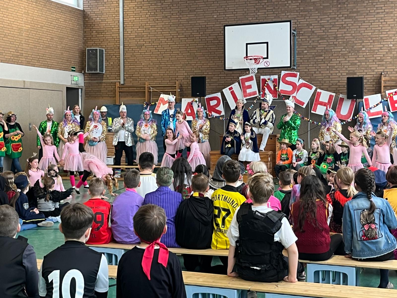 Hoher Besuch in der Marienschule
Prinzen und Prinzessinnen, Präsidentin und Präsident – alle in Amt und Würden, das war schon ein gewaltiger Aufmarsch, den die Hauenhorster Grundschule an Weiberfastnacht erleben durfte.
Nach den klasseninternen Feiern von 07:55 Uhr bis 09:00 Uhr versammelten sich alle Kinder und Lehrkräfte und auch einige Eltern in der festlich vorbereiteten Turnhalle und begrüßten unter tosendem Beifall Prinzessin Sara und Prinz Ruben, „die Großen“, wie Schulleiter Hülsmann das Prinzenpaar aus Hauenhorst betitelte und auch Prinzessin Anna und Prinz Ben, das amtierende Kinderprinzenpaar, oder mit Hülsmanns Worten „die Kleinen“  mit samt ihrem Gefolge, den Elferräten. Aber auch das Präsidentenpaar der KG DaLaHau, Sonja und Stefan Miethe ließen die Gelegenheit nicht aus, dem närrischen Treiben an „Ihrer“ Grundschule vor Ort beizuwohnen.
Und das kleine aber feine Programm hatte einiges zu bieten. Nette Worte, flotte Tänze, eine Proklamation zum Wohle aller Schülerinnen und Schüler, eine Aufführung der Bambinigarde, eine artistische Vorführung des Solomariechen Leni Fischer, ein JumpStyle-Auftritt des dritten Schuljahres und eine forsche Rede von Schulleiter Hülsmann, der mit seinem Kollegium verkleidet als Handwerker den Um- bzw. Neubau der Marienschule nach jahrelanger und fortwährender Wartezeit nun selber in die Hand nehmen wird. 
„Wir fangen dann mal an! 
Lehrer können alles, das ist ja wohl bekannt, 
auch handwerkliche Dinge, das wurde bisher nur verkannt. 
Die eine kann gut schrauben, 
ja ja, eigentlich kaum zu glauben,
die andere macht gern inneres Design, 
ganz viel Expertise, nicht nur bloßer Schein.
Auch Elektrik, Fliesenlegen und Polieren, 
mit uns Lehrern wird nun endlich was passieren.
Schräubchen hier und Dübel dort, 
Arbeit ist an jedem Ort.
Vorbilder? Ganz klar: Bob der Meister, 
schließlich können wir ja auch mit Pinsel und Kleister.
Und am Ende wird`s hier richtig fein,
im Rathaus wird man auf die Lehrer neidisch sein.
Wir wollen nicht mehr warten, drum werden wir jetzt starten.
In fünf Tagen sind wir dann am Ende, 
denn an der Marienschule helfen viele Hände.
Und wer jetzt sagt, „die haben ja ´nen Knall,
dem geb´ ich recht, alles nur ein Gag zu Karneval.
Nach vielen kurzweiligen Einlagen ging es dann als Polonaise Richtung Gemeindehaus und Kindergarten und anschließend zurück zur Karnevalsdisco in die Party-Aula, die der Hausmeister Matthias Silies zwischenzeitlich gemeinsam mit der Hilfe einiger Eltern ordentlich aufgepeppt hatte. Mit den Lieblingshits der Kids endete dann dieser „närrische Tag“ an der Marienschule. „Karneval an der Marienschule in Hauenhorst – Helau!“  