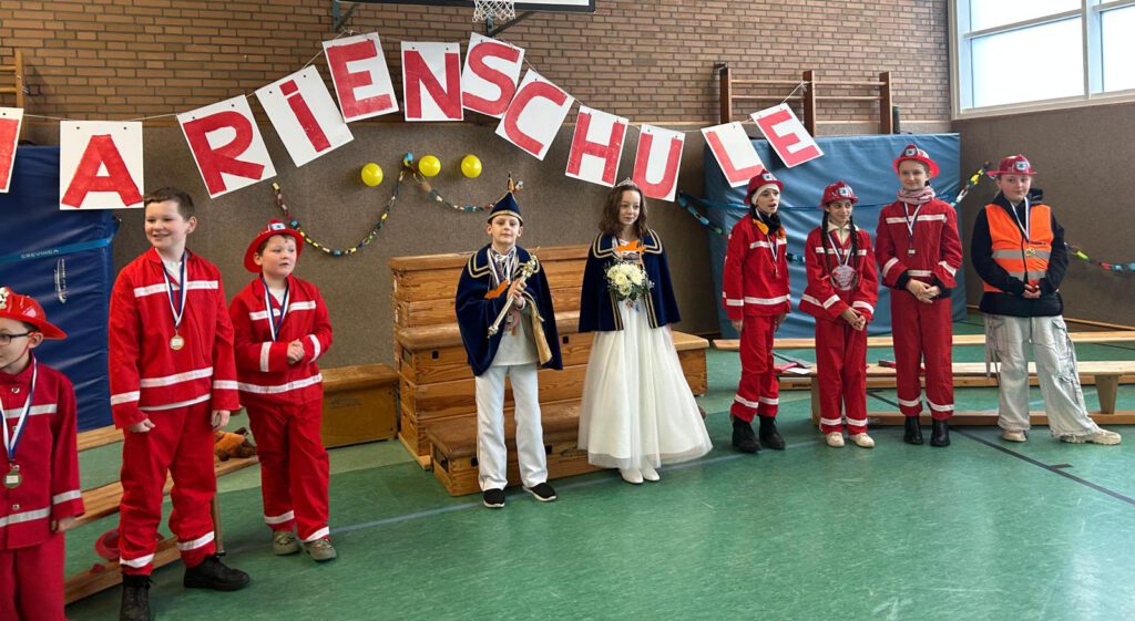 Hoher Besuch beim Schulkarneval in Hauenhorst Hauenhorst kann Karneval. Das ist sogar überregional bekannt und zieht viele karnevalistische Gruppen und Besucher zu diesem Brauchtumsfest in den Süden von Rheine. Natürlich wird diese Freude und Begeisterung am Karneval in vielen Hauenhorster Famlien gelebt, unterstützt und somit auch weitergegeben. Auch die Vereine vor Ort, mittlerweile alle unter einer Kappe, stellen jedes Jahr einen tollen Kinderkarneval auf die Beine. Auch die Grundschule vor Ort, die Marienschule, trägt gerne ihren Teil dazu bei und feiert intensiv jedes Jahr an Weiberfastnacht ihren Schulkarneval. Am liebsten so groß wie in diesem (und auch letzten Jahr), mit dem Besuch des großen und kleinen Prinzenpaares in der festlich geschmückten Halle der Marienschule. Prinzessin Ramona von Takt und Tanz und Prinz Pascal von Edel und Stahl schauten kurz vor ihrer Fahrt zum Stadtkarneval in der Schule vorbei und wurden von 196 jungen Närrinnen und Narren gebührend begrüßt Schulleiter Christian Hülsmann vermutete in den Initialien des Prinzenpaares“RP“ (Ramona und Pascal) das Regierungspräsidium und sprach von einer „Abordnung von höchster Stelle, die begrüßen wir gebührend mit einer riesen Welle“. Dreifacher Tusch. Auch an der Tatsache, dass die beiden Hauenhorster Urgesteine genau die richtige Wahl sind, ließ Hülsmann keinen Zweifel: „Prinzessin Ramona, aus dem Hause Takt und Tanz, genau die richtige, da sind wir sicher, und zwar ganz und Prinz Pascal, aus dem Hause Edel und Stahl, auch das ist eine ganz, ganz feine Wahl.“ Und dann wurden auch schon schnell die Orden ausgetauscht und ab ging es für die Großen zum Bus nach Rheine. Bis 11:11 Uhr blieb nicht mehr viel Zeit. Viel Zeit hatte die Schule dann aber für das Kinderprinzenpaar samt Gefolge. Prinzessin Alica aus dem Hause Klein und Beerig und Reinhard von wild und waldig verlasen die Proklamation und hatten schnell die weiteren 194 Schülerinnen und Schüler auf ihrer Seite. Hausaufgabenfrei bis Aschermittwoch, Süßigkeiten ohne Ende und fünf Tage ohne elterliche Befugnisse-da waren alle Kids natürlich sofort mit einverstanden und feierten ihr Prinzenpaar. Ein absolutes Highlight war dann der „Heidi-Auftritt“ der Bambinigarde der KG DaLaHau, die gleich zweimal auftreten durften und auch noch durch eine flotte Zugabe brillierten. Und wie immer ging es nach dem offiziellen Teil nahtlos zur Karnevalsdisco über, die die Aula noch bis kurz vor 14:00 Uhr mit toller Musik und tanzenden Kindern füllte. Am Freitag war dann aber auch schon wieder fast normaler Unterricht. Schließlich sei die Schule ja kein Festzelt, wie Hülsmann betonte. Und die Hausaufgabe, die es eigentlich gar nicht hätte geben dürfen, bestand dann darin, dass alle Kinder aktiv oder passiv am Hauenhorster Karnevalsumzug am Sonntag teilenehmen sollten.
